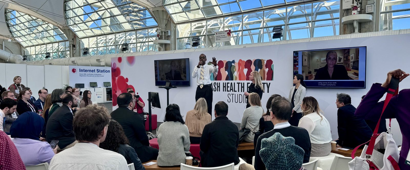 Oya Gilbert presenting from the stage of the ASH Health Equity Studio to an audience of hematology clinicians and researchers.